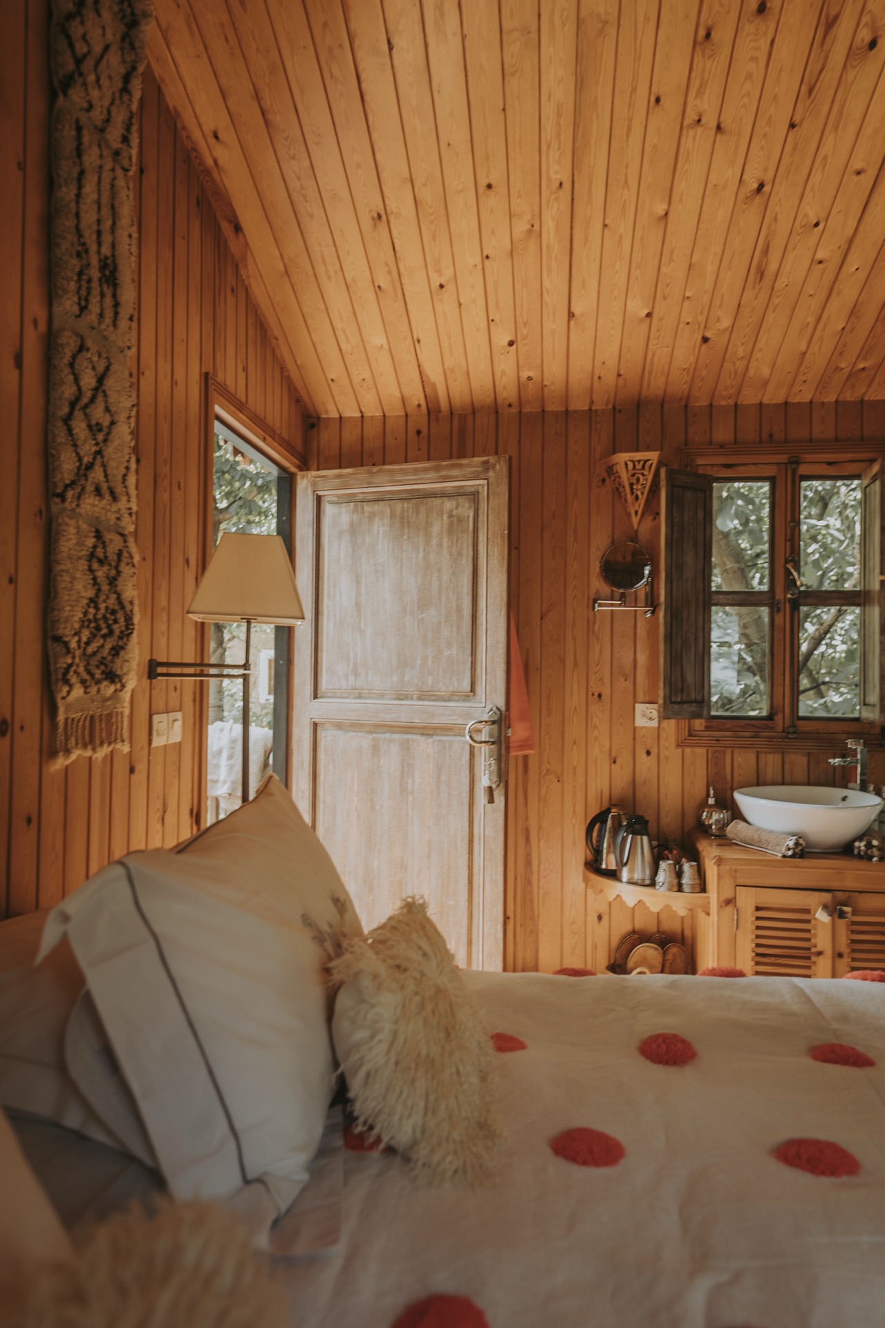 Intérieur tout en bois de la Romantic Tree House, lit à pompons et lumière chaude