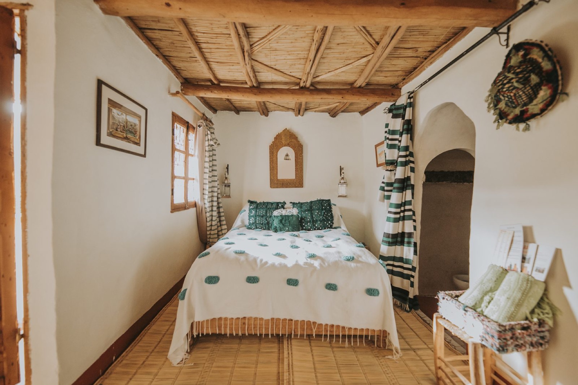 Chambre de la maison principale éclairée à la bougie, murs de pisé et textiles berbères
